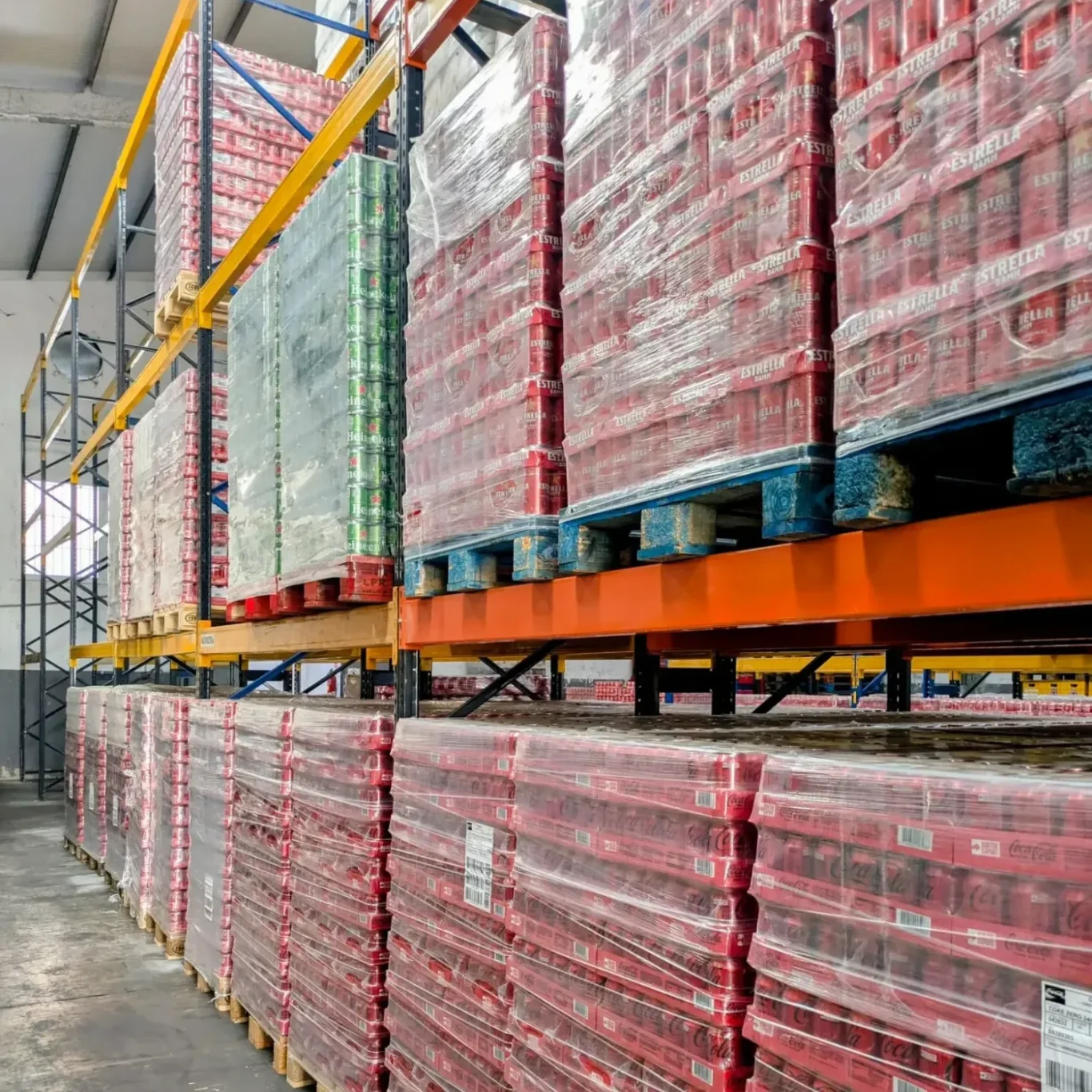 Estantes altísimos con palets de cajas de coca colas apiladas en un almacén.