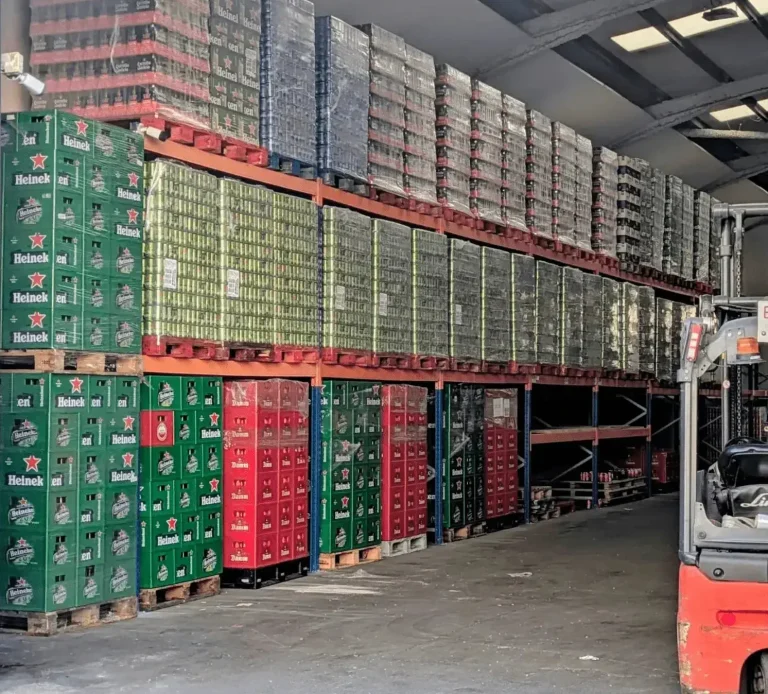 Licores en Bebidas Barcino Botellas de licor Seagram's Extra Dry frente a cajas de cerveza roja.