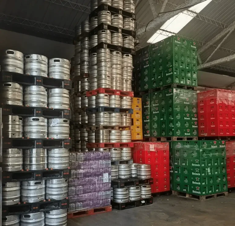 Licores en Bebidas Barcino Botellas de licor Seagram's Extra Dry frente a cajas de cerveza roja.